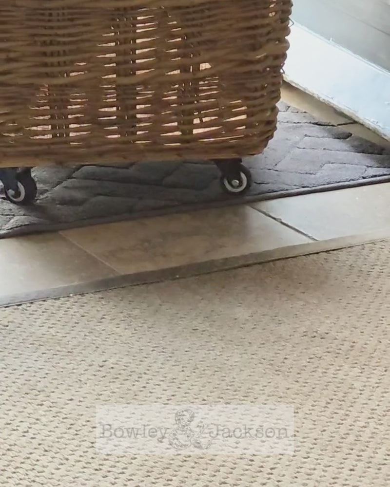 Log basket on wheels being wheeled through an entrance hall.