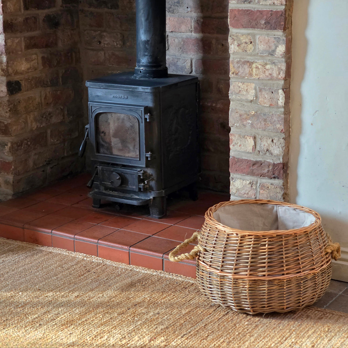 Small round log basket next to wood burning stove.