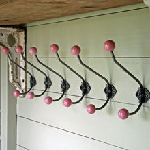 Row of six antique finish pink cast metal rosette double coat wall hooks